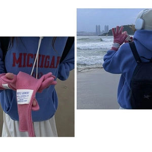 Detailed view of pink knitted wool gloves with woven patch and beach lifestyle usage