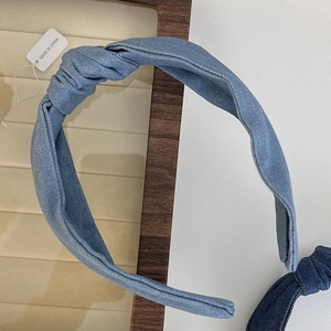 Detailed close-up of light blue denim knotted headband with pleated fabric texture