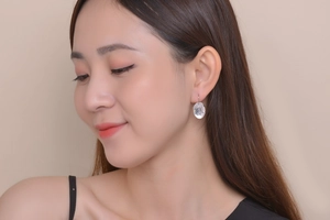 Close-up of elegant silver oval earring with clear crystals worn by a model