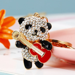 Close-up of rhinestone panda keychain with a red guitar on a pink decorative plate
