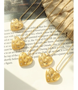 Detailed close-up of five golden heart necklaces with quilted patterns and small zircons