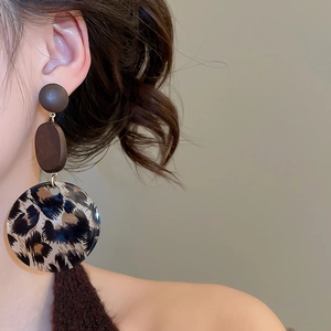 Nahaufnahme von Retro-Ohrringen mit Leopardenmuster aus Acryl und Holz am Modelohr