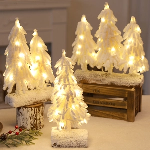Mini LED Christmas tree with snow flocking and warm yellow lights on a wood base