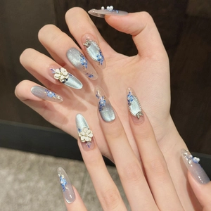 Detail of blue cat eye press-on nails with 3D white flowers and elegant pearl accents