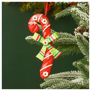 Close-up of a festive candy cane ornament with flower detail hanging on a snowy tree branch