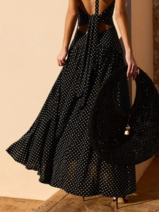 Summer black polka dot halter maxi dress with backless design and a woven handbag