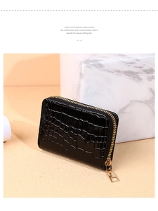 Detail of black crocodile texture card holder wallet with golden zipper on a marble stand