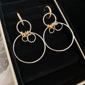Macro shot of geometric intertwined gold and silver circle earrings on black velvet
