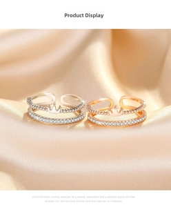 Detailed view of crown-shaped double-layer rings with zircon inlay on silk background