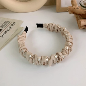 Vista dettagliata del cerchietto in tessuto plissettato beige con eleganti perle finte