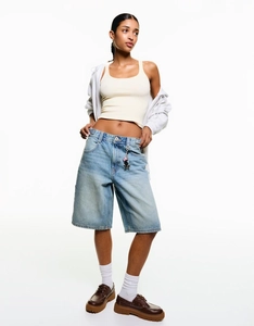 Detail der lockeren blauen Denim-Shorts mit Sternanhänger und beigem Tanktop für Damen