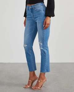 Detail shot of distressed blue high-waisted jeans with knee rips and raw hems