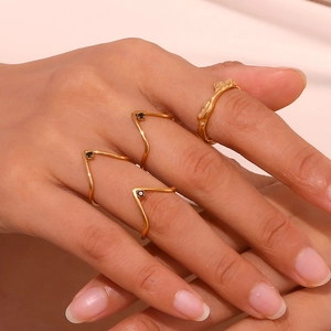 Close-up of stacked 18K gold-plated V-shaped rings with black diamond micro-pave on model