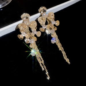 Sparkling flower drop earrings with golden tassels and crystal details on dark background