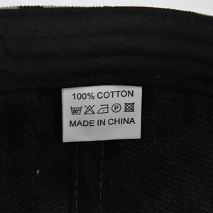 Detail showing the internal care label and 100% cotton material of the black baseball cap
