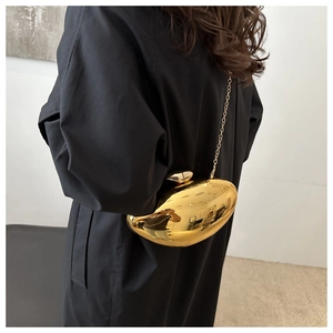 Golden mango-shaped acrylic clutch bag with metal chain shown on model