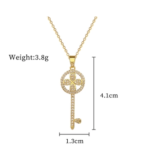 Macro detail of gold key necklace pendant with sparkling zircon floral inlay and dimensions