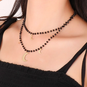 Close-up of double-layer necklace with black beads and gold moon pendants on a model