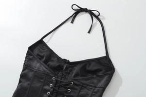 Dettaglio del corsetto in raso nero con allacciatura frontale e occhielli d'argento
