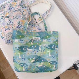 Détail de sacs fourre-tout en toile avec motifs de fleurs et lapins et étiquette simple