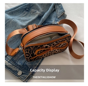 Detail view of leopard print crossbody bag with dual zippers and bow decoration