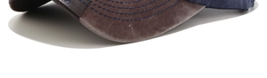 Macro detail of washed brown canvas baseball cap brim with blue embroidered lettering