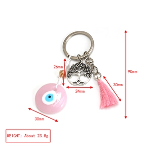 Detail view of pink evil eye keychain with tree of life charm and silk tassel pendant
