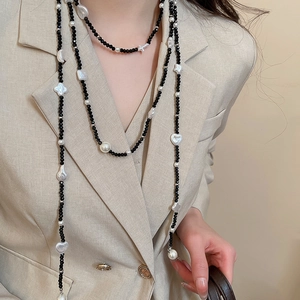 Close-up of layered necklace with black crystals, baroque pearls, and star heart charms