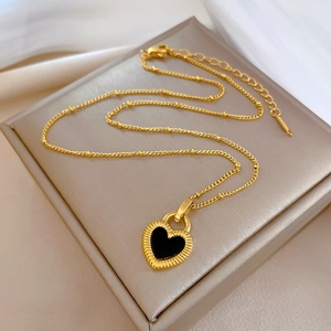 Close-up of golden titanium necklace with heart shell pendant and beaded chain details