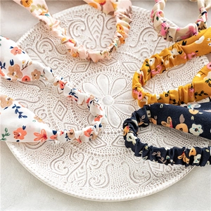 Floral print elastic headbands in various colors displayed on an elegant white ceramic plate