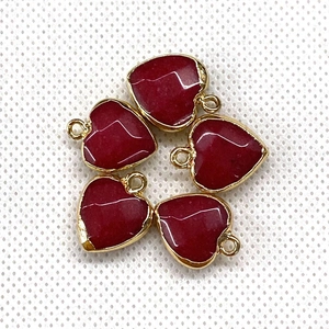 Detailed view of red heart-shaped gemstone pendants with golden metal frames and hoops