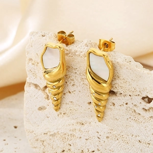 Detailed close-up of gold conch shell earrings with mother-of-pearl and diamonds