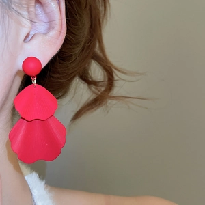 Macro detail of red layered flower petal earrings with matte finish and gold accents