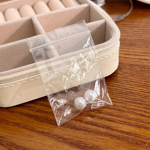 Minimalist pearl stud earrings in a protective PE bag on a soft velvet jewelry box