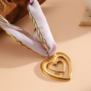 Dettaglio dei ciondoli a cuore placcati oro 18K su una collana foulard di seta floreale