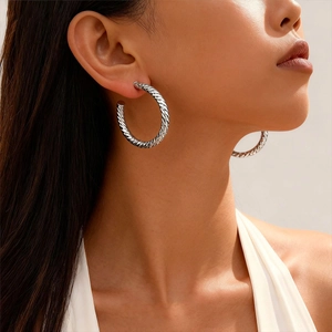 Silver geometric twisted hoop earrings worn by model showing minimalist texture