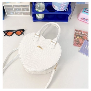 Vue de dessus d'un sac à main blanc en forme de cœur avec motif crocodile et or