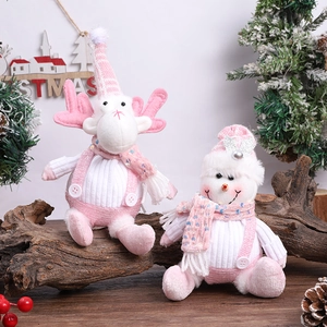 Pink and white reindeer and snowman plush dolls on rustic wood for Christmas decor