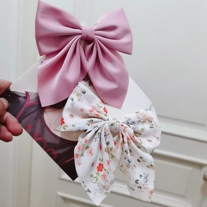 Detail of pink satin bow and white floral print hairpin set with smooth texture