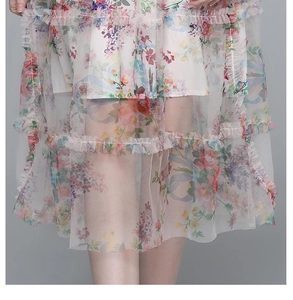 Détail de l'ourlet à volants sur robe en tulle fleuri montrant le tissu et l'imprimé