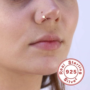Macro shot of a gold heart-shaped S925 sterling silver nose ring worn by a model