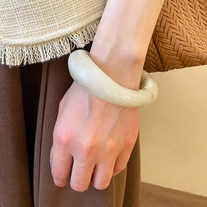 Close-up of minimalist resin bangle featuring polished off-white texture and marbled finish