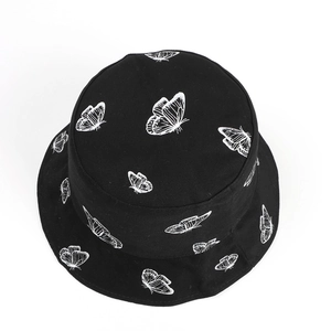 Vue détaillée d'un chapeau bob noir avec motifs de papillons blancs et texture en toile