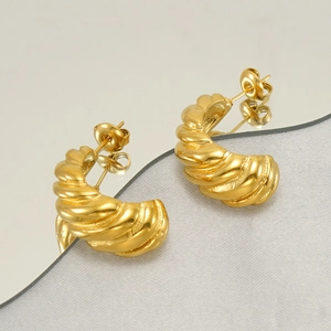 Détail de boucles d'oreilles croissant dorées avec finition polie et mate sur miroir