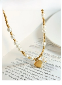 Detailed macro view of a gold heart pendant on a white pearl and gold bead necklace