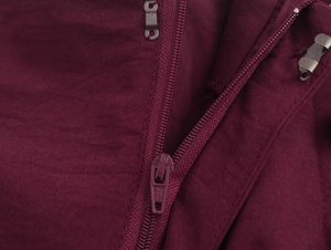 Detailed close-up of burgundy high-waist trousers with zipper and metal hook closures