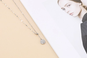 Detailed view of silver coin pendant necklace with adjustable bead on minimalist chain