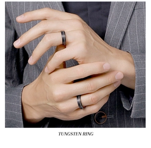 Close-up of a minimalist black tungsten ring worn by a male model in a business suit