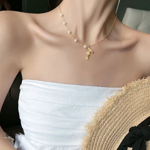 Detail of gold fishtail pendant necklace with pearls on a female model neck