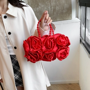 Detailed view of red silk evening bag with 3D rose flowers and beaded handle